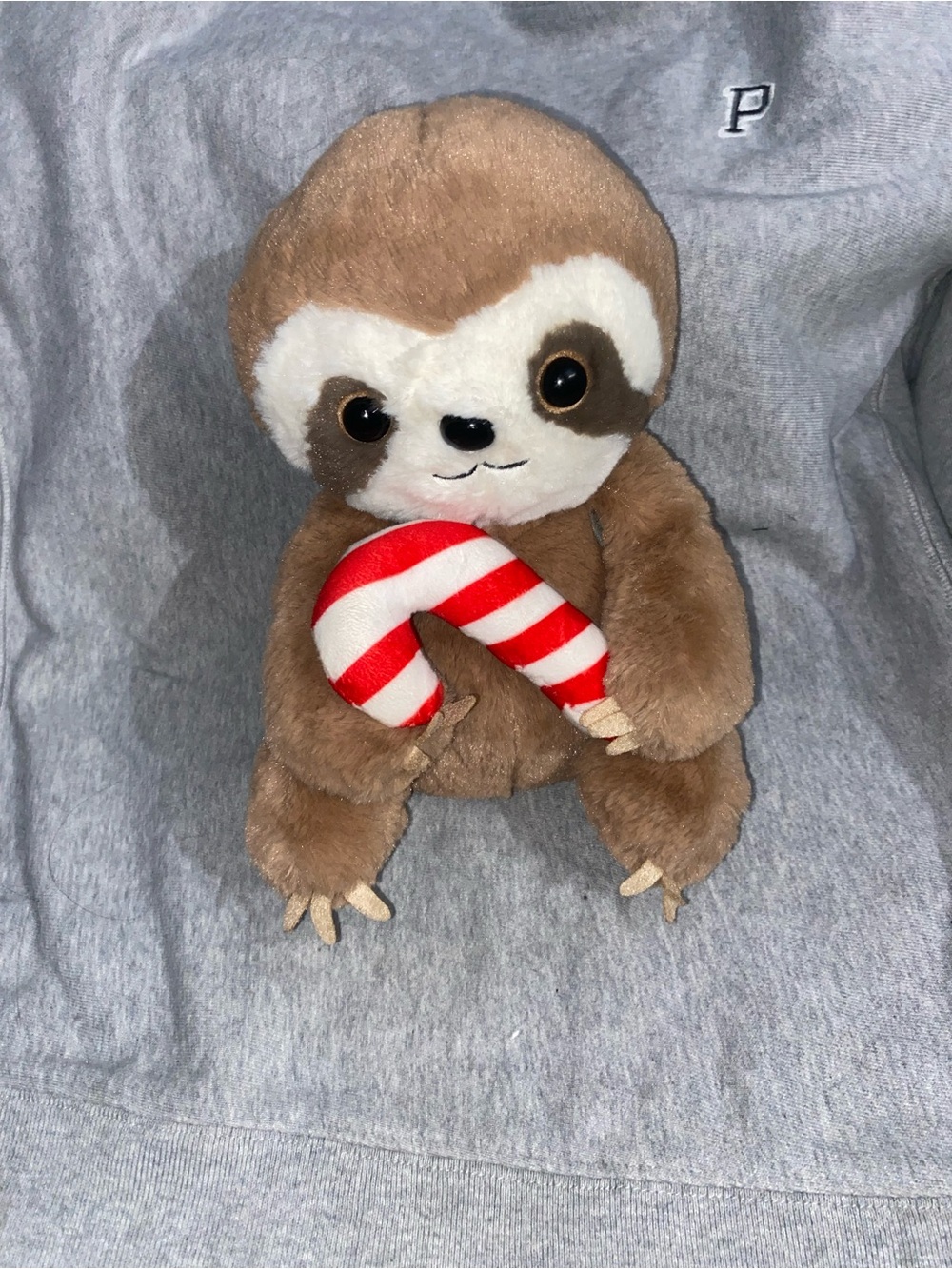 Sloth plush toy holding a candy cane